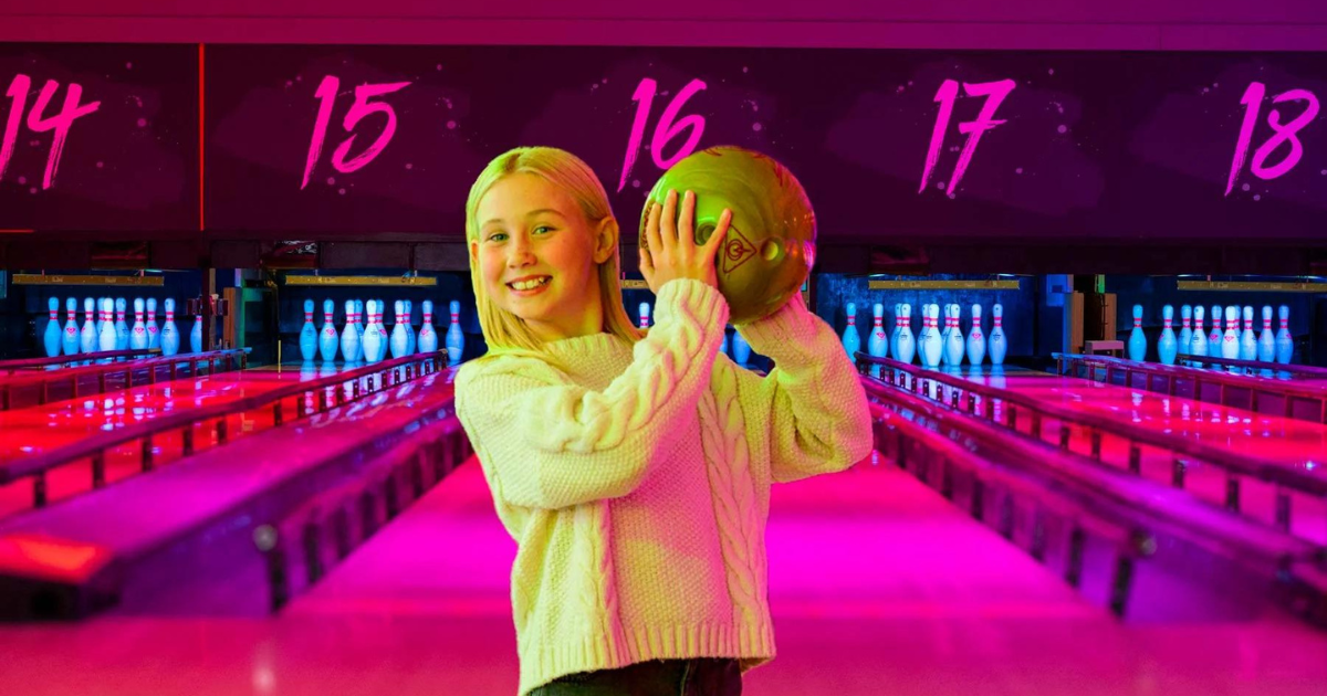 young girl holding bowling ball at tenpin